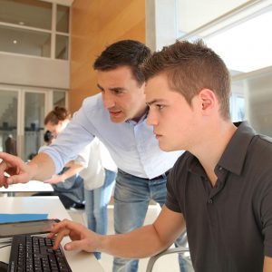 Teacher and student working on computer