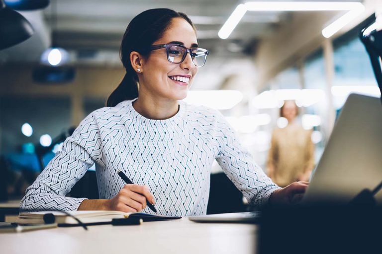 Cheerful businesswoman excited with accomplished project successfully monitoring news online via netbook, smiling female administrative manager happy about increasing company income making report